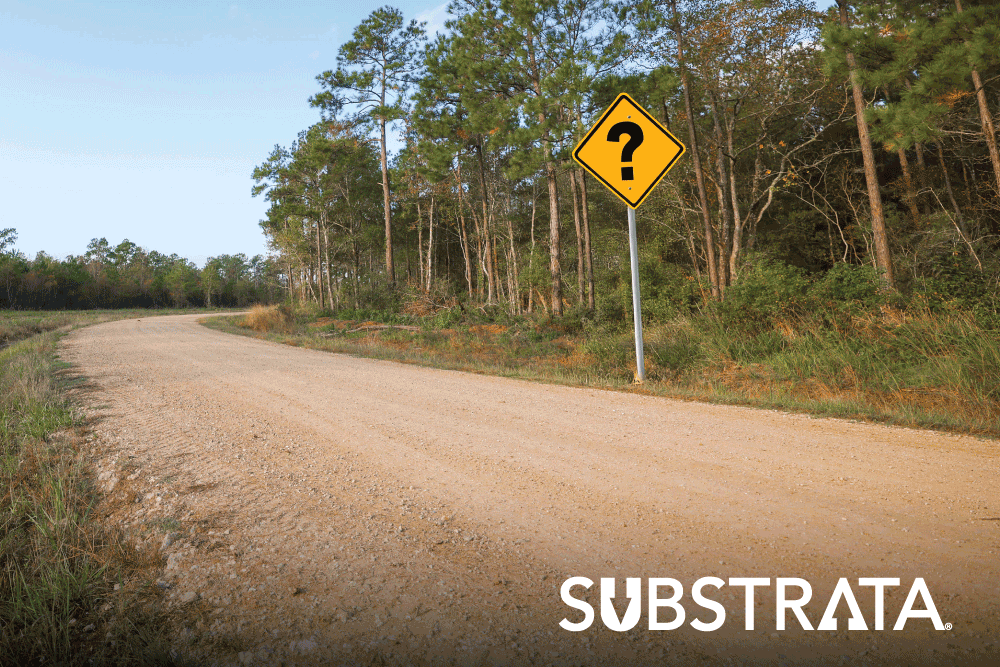 Perma-Zyme treated dirt road with a question mark on a road sign