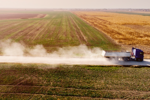 Truck kicking up dust driving down a road