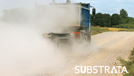 Heavy duty haul truck trailing a massive dust cloud on a private road